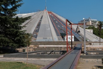 De Piramide van Tirana, gebouwd om als museum over de dictator Enver Hoxha te fungeren. Na zijn dood is het in verval geraakt. De vredes klok ervoor is gemaakt van overgebleven kogels.